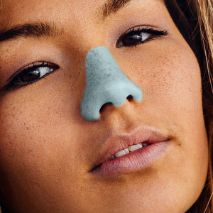 close up image of a brown-haired lady with Noz neon sunscreen in the color blue on her nose