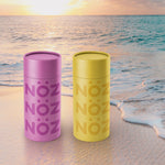 Load image into Gallery viewer, purple and yellow Noz sunscreen tubes sitting in front of a breaching wave
